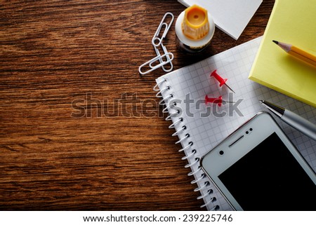 Close up Various Educational Supplies and Mobile Phone Gadget on Brown Wooden Table with Copy Space for Texts on the Left Side.