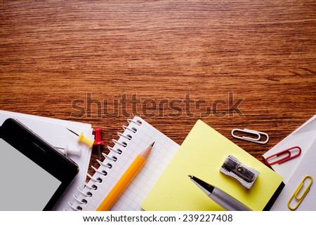 Close up Various Educational Supplies and Mobile Phone Gadget on Brown Wooden Table with Copy Space for Texts .