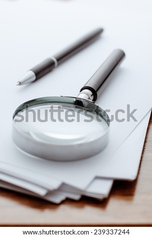 Magnifying glass, ballpoint pen close-up on white paper for notes
