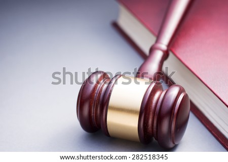 High Angle View of Cherry Wood Gavel with Brass Band Resting on Book Bound in Red Leather in Justice Concept Image with Copy Space