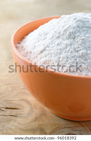 white flour in the orange bowl on the table