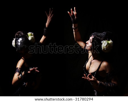waist portrait of two female dancers in oriental costumes on black background