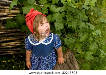 little girl in blue country-style dress and red hat shouting