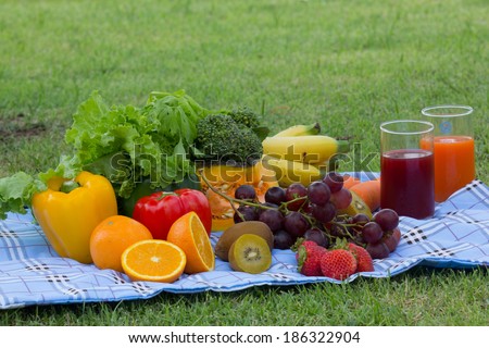 Colorful bowl of tropical fruit salad with Orange  kiwifruit and fruit juice at the picnic in the grass
