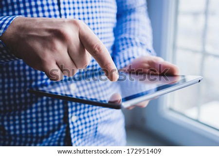 The man uses a tablet PC. Modern gadget in hand.