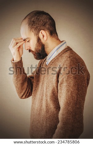 man with a beard in brown sweater sad about troubled deep thought