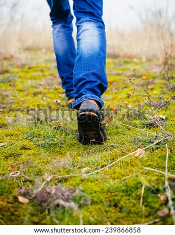 Person wearing walking shoes takes a step on a mountain hiking path, closeup photo.