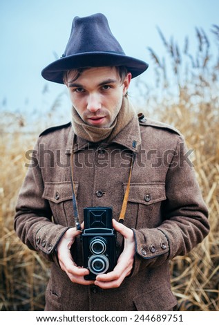 Man hand holding retro photo camera outdoor Lifestyle concept with  autumn nature on background