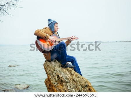 young man playing on guitar at the lake
