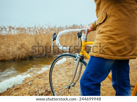 a young man with hands on the steering wheel of bicycle near the lake