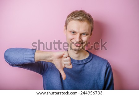 Handsome young man lowered his fist with the thumb down. Close portrait. disgruntled gesture.