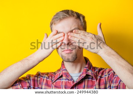 Portrait of a young man covering his eyes with his hand