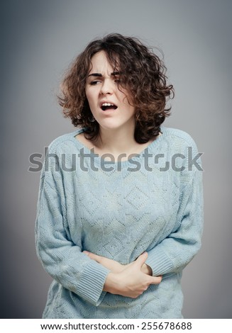 A woman suffering from severe pain in her tummy. Isolated on white.