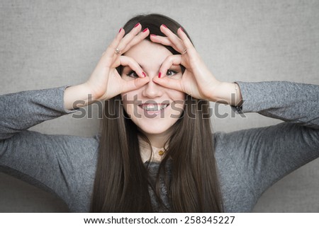 Young happy woman holding her hands over her eyes as glasses