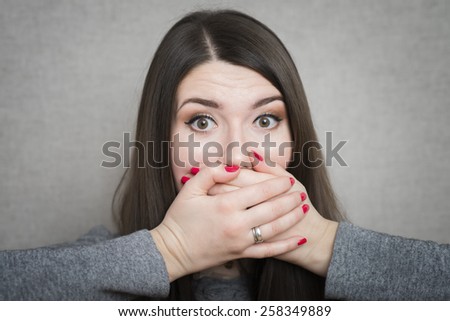 young woman covering her mouth by the hands while standing isolated on white