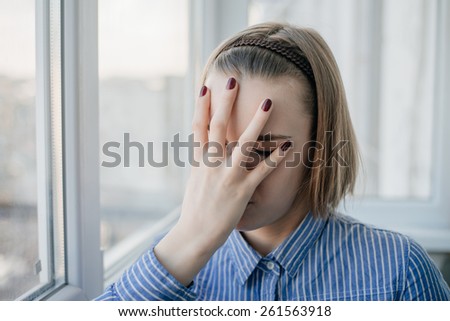 young attractive woman suffering depression and stress standing alone in pain and grief against window feeling sad and desperate at home with studio backlight