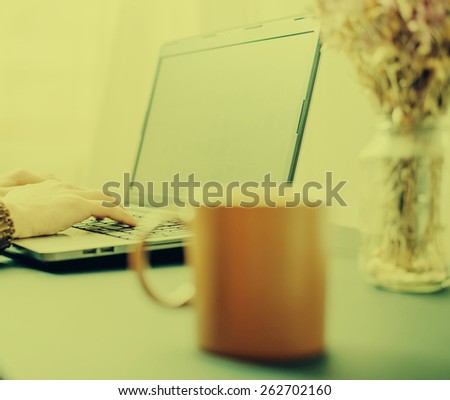 Office desk table with laptop computer, coffee cup and flower.