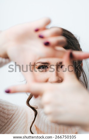 brunette girl doing camera hands and fingers on a white background