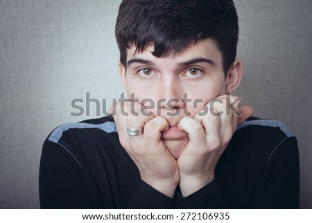 portrait of brunette man scared and keeps finger in mouth