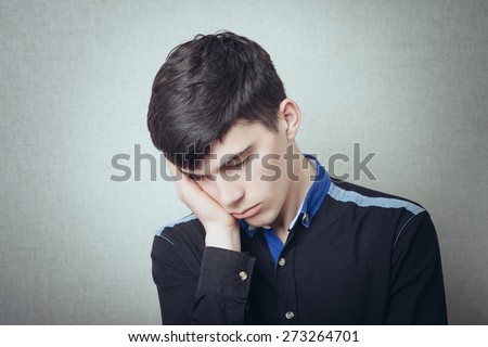 A man with his head on his hand is asleep. Tired, sleepy, gesture. On a gray background