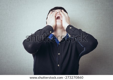 hands on face crying man on a gray background