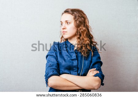 Curly woman folded her arms. On a gray background.