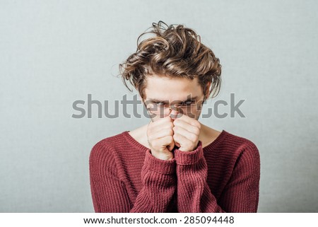 The man covered his face with his fists, frustrated. On a gray background.