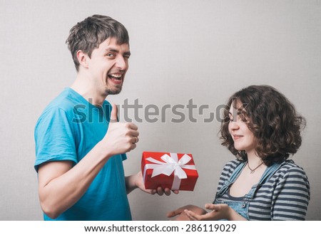 Valentine Gift. Happy Young Couple with Valentine\'s Day Present.  Happy Man giving a gift to his Girlfriend. Holiday
