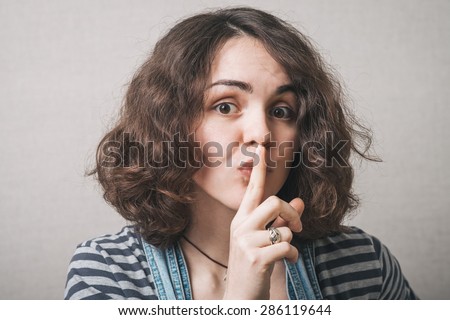 Beautiful woman with secret holding finger over lips.
