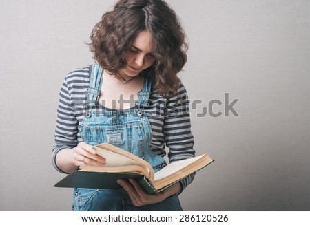 girl with big book in hand in hand on a gray background