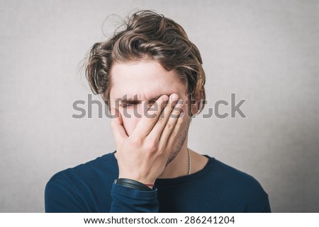 The man was crying, very upset, he covered his face with his hands. Gray background