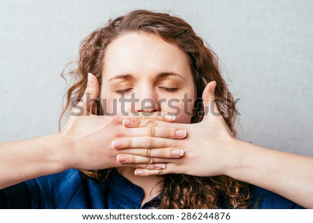 The woman closed her hands over her mouth. Gray background