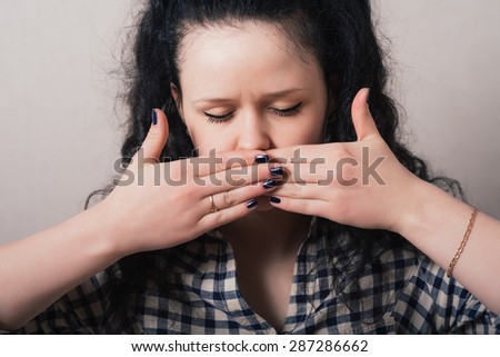 girl covers her mouth with her hands