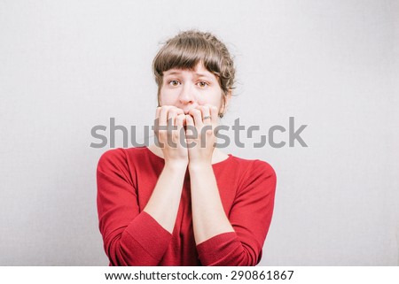 Women nervous nail biting. On a gray background.