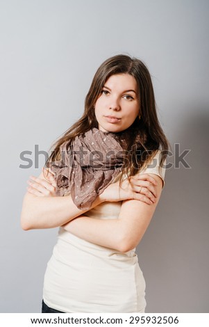 Young woman folded her arms. On a gray background.