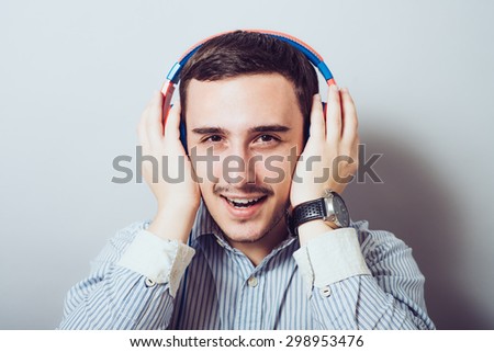 Cheerful guy enjoying loud music holding them tightly to ears