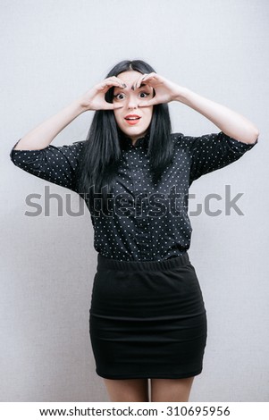woman surprised looking through fingers like binoculars searching something