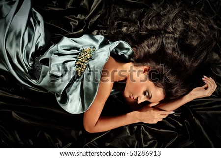 Young girl with long black hair lying poses no iridescent fabric