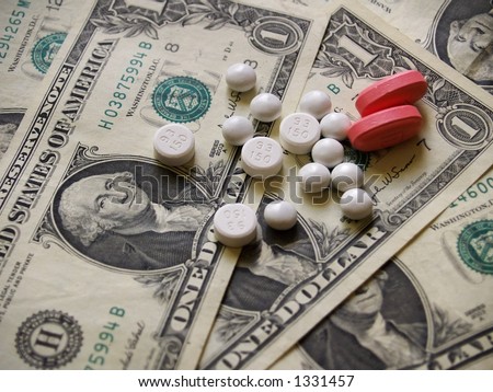 Pink and two types of white pills against a background of US currency or money in the form of dollar bills.