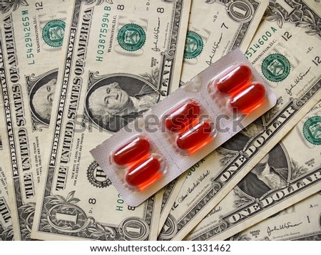 Orange gel caplets in a foil package against a background of US currency or money in the form of dollar bills.