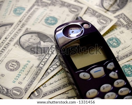 A dark purple mobile cellular telephone against a background of US currency or money in the form of dollar bills.