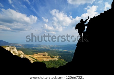 Silhouette climber conquers mountain peak