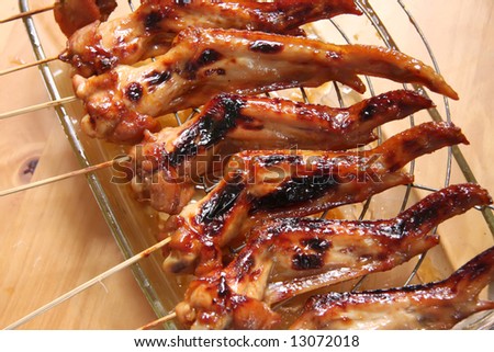 Grilled cooked chicken wings on wooden skewers