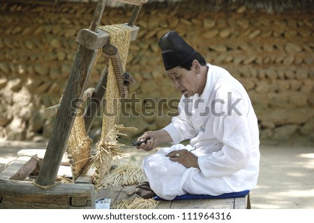 YONGIN, KOREA - AUGUST 6: An artisan at the Korean folk Village in Yongin, Korea works his craft of weaving on August 6, 2012. The Korean folk village displays life in Korea as it used to be.