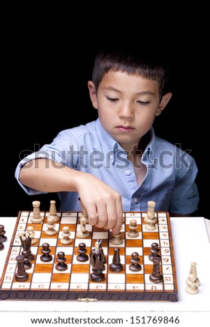 A young chess player starts to make a move on the chess board.