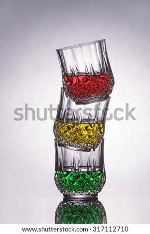 Three crystal glasses filled with color liquid in a crooked stack.