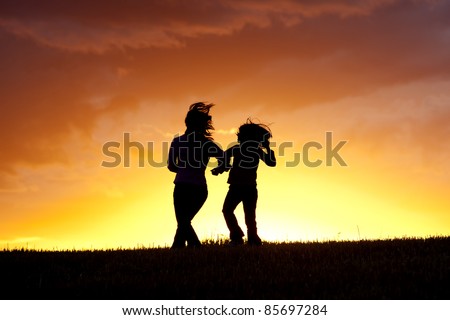 A mother and her daughter do a little dance at sunset.