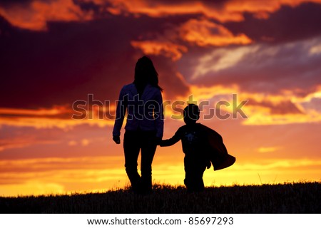 A tender moment of a mom and her son walking along at sunset.