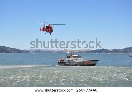 A red rescue helicopter and gray rescue boat in the water