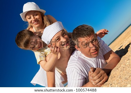 Photo of  family lying on sand on background of blue sky